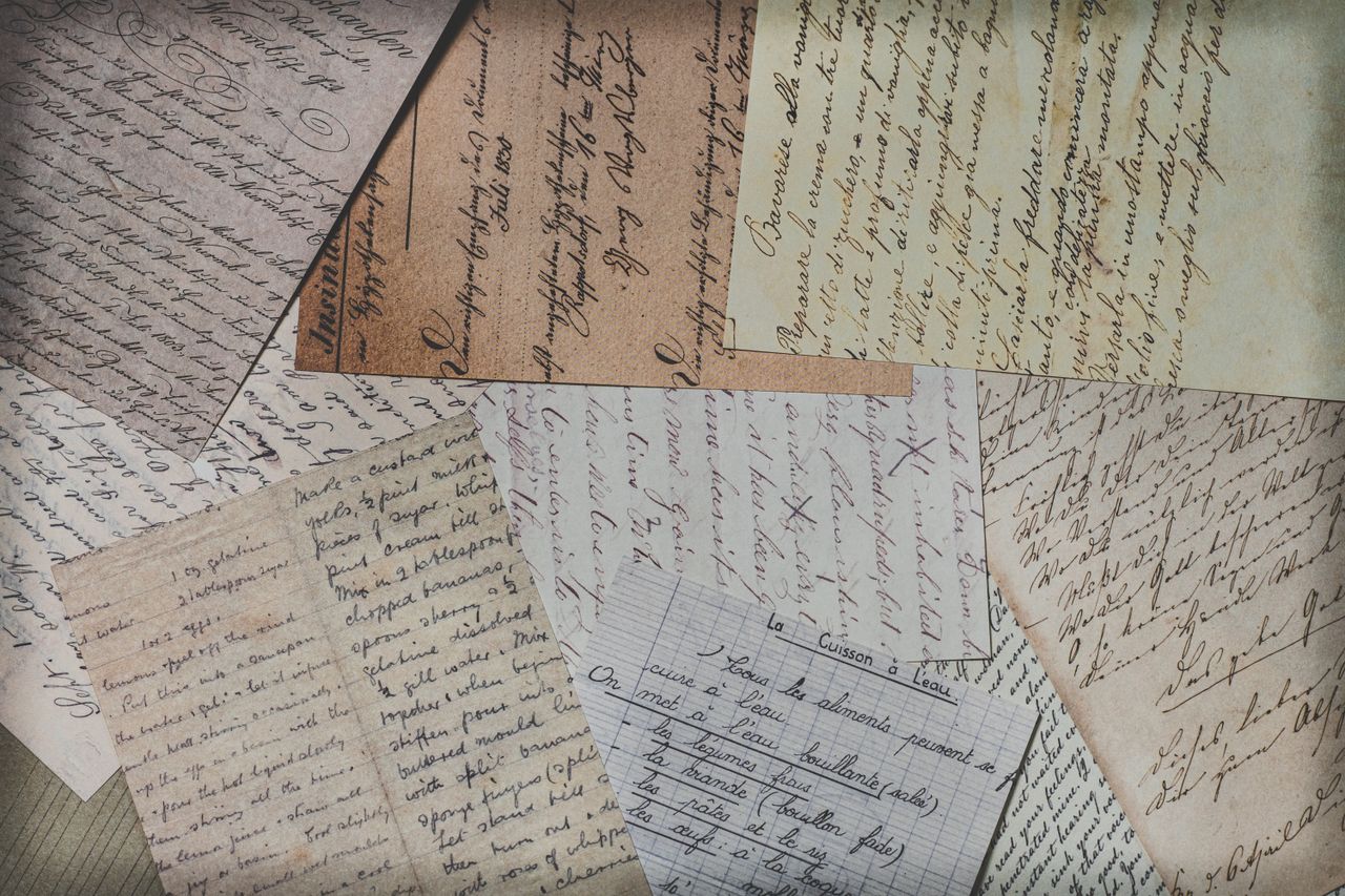 Close-up of various vintage handwritten letters on mixed paper textures, showcasing elegant penmanship.
